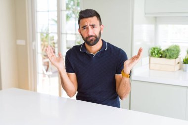 Evde yakışıklı İspanyol adam clueless ve kollar ve elleri ile karıştı ifade kaldırdı. Şüphe kavramı.