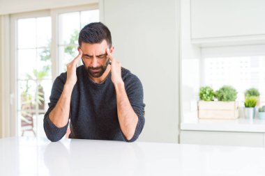 Yakışıklı İspanyol adam stres nedeniyle baş ağrısı için başını eliyle rahat kazak giyiyor. Acı çeken migren.