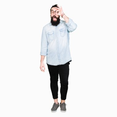 Uzun saç ve sakal ok jest yapıyor gözlüklü genç hipster adamla sürpriz yüz, göz parmaklarının arasından seyir ile şok. İmansız ifade.