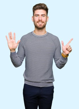 Çizgili süveter gösterme ve parmakları ile işaret giyen genç yakışıklı adam kendinden emin ve mutlu gülümseyerek süre yedi numara.