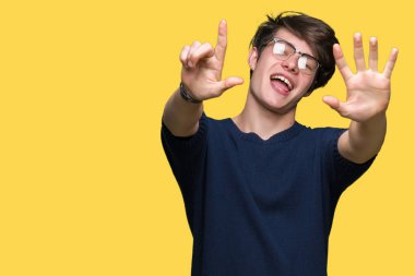 Gösterilen arka plan üzerinde gözlük takan genç yakışıklı adam izole ve parmakları ile işaret kendinden emin ve mutlu gülümseyerek süre yedi numara.