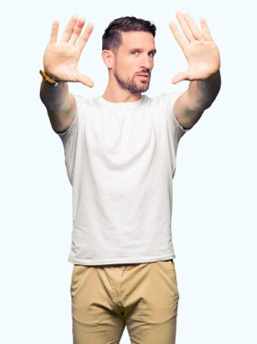 Yakışıklı adam çerçeve kullanarak yaparken rahat beyaz t-shirt gülen giyen eller avuç içi ve parmaklar, kamera perspektif