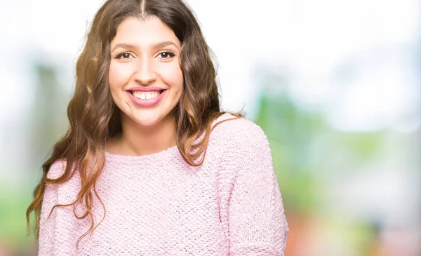Genç güzel kadın yüzünde mutlu ve serin bir gülümseme ile pembe kazak giyiyor. Şanslı kişi.