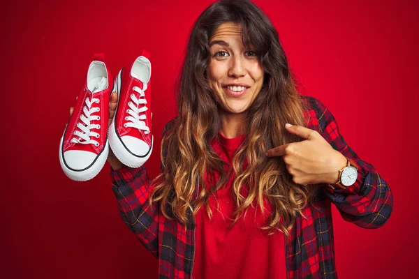 Mujer Hermosa Joven Sosteniendo Zapatillas Pie Sobre Fondo Rojo Aislado —  Fotos de Stock
