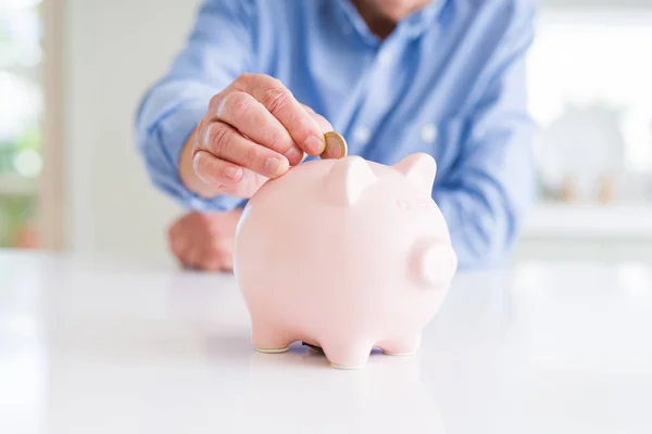 Close-up de homem colocando uma moeda dentro do banco porquinho como poupança — Fotografia de Stock
