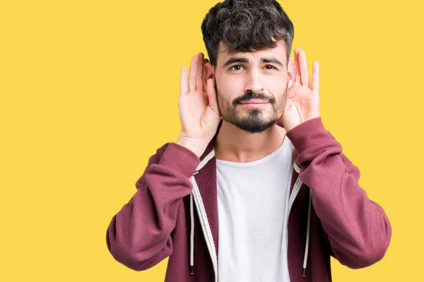 Jovem Bonito Sobre Fundo Isolado Tentando Ouvir Ambas Mãos Gesto — Fotografia de Stock