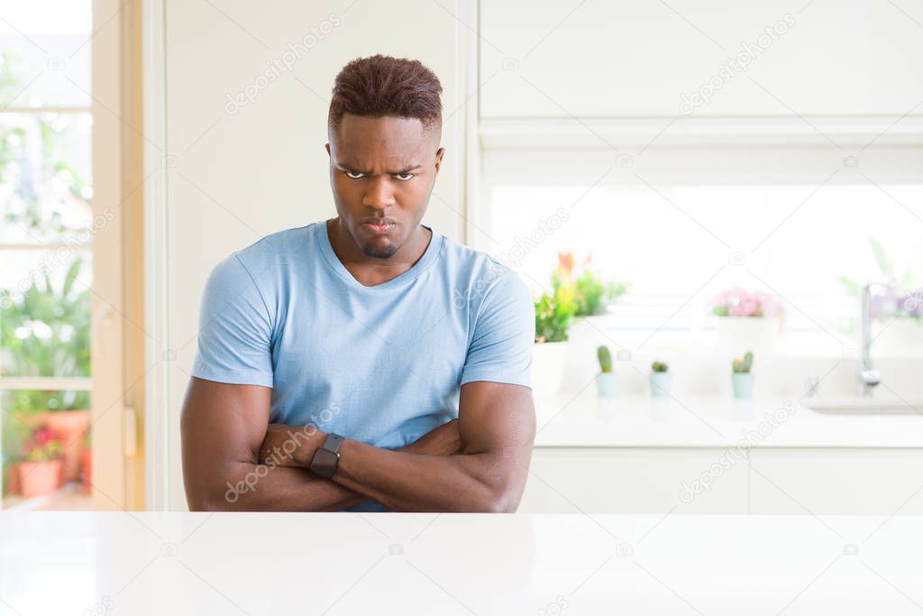 Handsome african american man wearing casual t-shirt at home skeptic and nervous, disapproving expression on face with crossed arms. Negative person.
