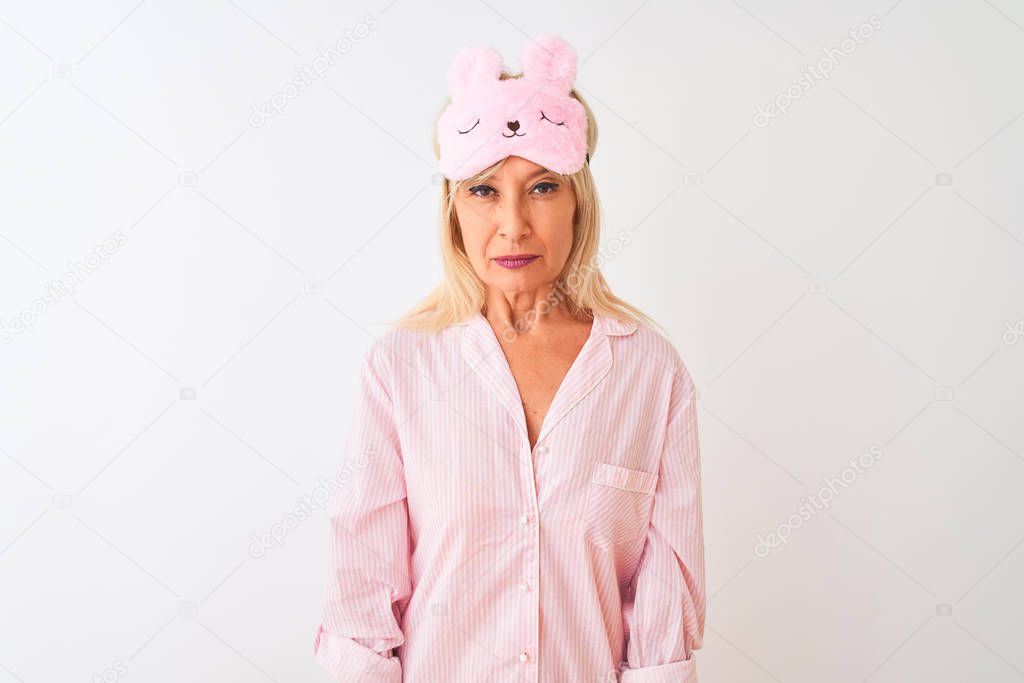 Middle age woman wearing sleep mask and pajama over isolated white background skeptic and nervous, frowning upset because of problem. Negative person.
