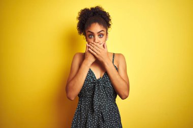 Izole sarı arka plan üzerinde yaz rahat yeşil elbise giyen Afrikalı Amerikalı kadın hata için elleri ile ağız kapsayan şok. Gizli kavram.