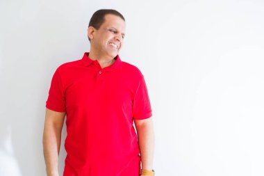 Orta yaş adam beyaz duvar üzerinde kırmızı t-shirt giyen yüzünde gülümseme ile yan bakmak, doğal ifade. Güven gülüyor.