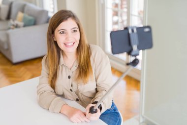 Mutlu bir yüz ayakta ve dişleri gösteren kendinden emin bir gülümseme ile gülümseyerek selfie sopa kullanarak bir resim çekmek güzel genç kadın