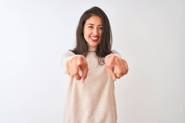 Yalnız beyaz arka plan üzerinde duran boğazlı kazak giyen güzel Çinli kadın sizi ve parmakları ile kamera işaret, olumlu ve neşeli gülümseyen