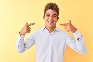 Genç yakışıklı işadamı izole sarı arka plan üzerinde zarif gömlek giyen neşeli gösteren gülümseyerek ve parmakları diş ve ağız ile işaret. Diş sağlığı kavramı.