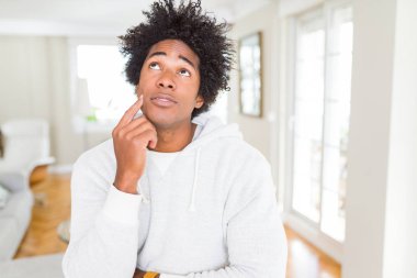 Afrika kökenli Amerikalı adam çene düşünme hakkında soru, dalgın ifade üzerine el ile kazak giyiyor. Düşünceli yüzüyle gülümsüyor. Şüphe kavramı.