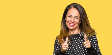 Moda ceket işaret parmakları için fotoğraf makinesi ile mutlu ve komik yüz giyen güzel orta yaş kadın. İyi enerji ve vibes.