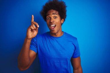 Afro saçlı Afro saçlı afro-amerikan adam izole mavi arka plan üzerinde duran başarılı bir fikir ile parmak işaret. Çıktı ve mutlu. Bir numara.