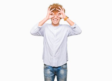 Afro saçlı, zarif gömlek giyen genç yakışıklı iş adamı dürbün gibi tamam jest yapıyor dilini dışarı yapıştırıyor, gözleri parmaklardan bakıyor. Çılgın ifade.