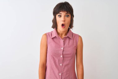 İzole beyaz arka plan üzerinde duran kırmızı yazlık gömlek giyen genç güzel kadın korkmuş ve sürpriz ifade ile şok, korku ve heyecanlı yüz.