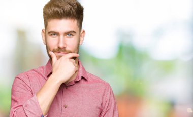 Genç yakışıklı iş casual adam emin çapraz kollar ve çeneme kaldırdı el ile gülümseme ile kameraya bakıyor. Pozitif düşünce.