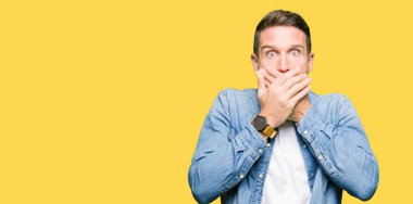 Mavi gözlü ve sakallı kot ceket giyen yakışıklı adam hata için elleri ile ağız örtülü şok. Gizli kavram.