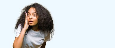 Casual beyaz t-shirt el gizli söylenti söylüyor dudaklarından giyen kıvırcık saçlı Genç güzel kız kötü amaçlı konuşma konuşma fısıldayan