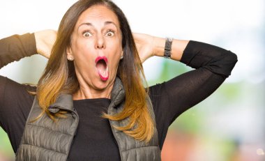 Kış yeleği deli ve baş, korkuyor ve açık ağzı ile şok sürpriz elleriyle korkuttu güzel orta yaş kadın