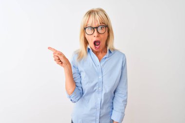 Izole beyaz arka plan üzerinde zarif gömlek ve gözlük giyen orta yaş iş kadını yan parmak ile işaret şaşırttı, açık ağız hayret ifade.