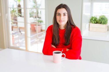 Yüzünde ciddi bir ifade ile siyah kahve içme güzel ve genç birbayan. Basit ve doğal kameraya bakıyor.