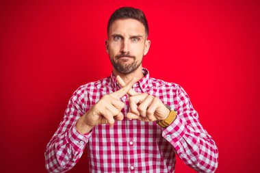 Kırmızı izole arka plan Reddi ifade geçiş parmakları üzerinde negatif işaret yapıyor genç yakışıklı adam