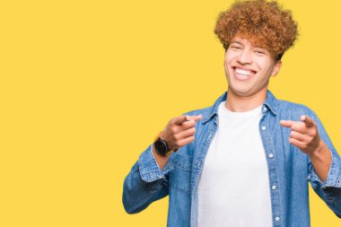 Yakışıklı genç afro saçlı kot ceket işaret parmak kamera ile mutlu ve komik yüz için giyiyor. İyi enerji ve vibes.