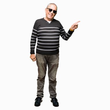 Kameraya bakarak yan el ve parmak ile işaret yüzünde, kış kazak ve kocaman bir gülümseme ile güneş gözlüğü takan yakışıklı komuta sizde.