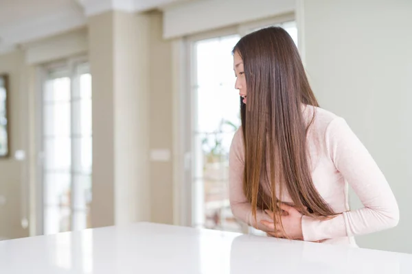 美丽的亚洲妇女穿着休闲毛衣在白色桌子上 手在胃上 因为消化不良 疼痛生病感觉不适 疼痛概念 — 图库照片