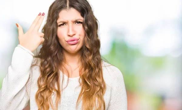 Beyaz kazak giyen genç güzel kadın Çekim ve kendini gösteren el ve parmakları kafaya, intihar jesti.