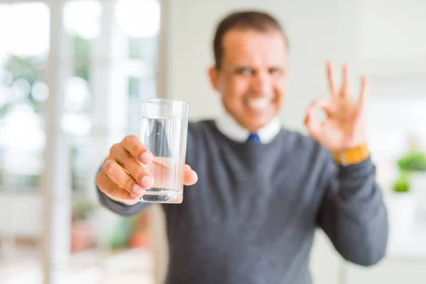 自宅で水のコップを飲む中年男性は指でOkサインをする 優れたシンボル — ストック写真