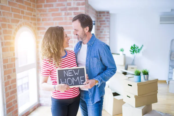 Orta yaş Senior çift yeni bir eve hareket, yeni bir ev metin ile bir tahta tutan Apartmant aşık mutlu gülümseyen