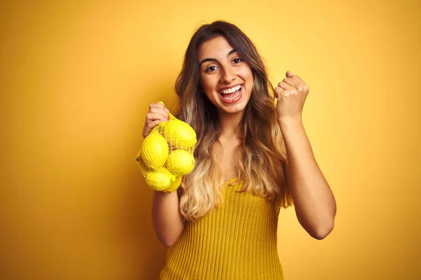 Mladá Krásná Žena Která Drží Síť Citronů Přes Žluté Izolované — Stock fotografie