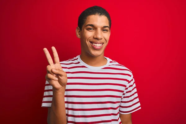 年轻的英俊阿拉伯男子穿着条纹T恤在孤立的红色背景显示和指向手指二号 同时微笑自信和快乐 — 图库照片