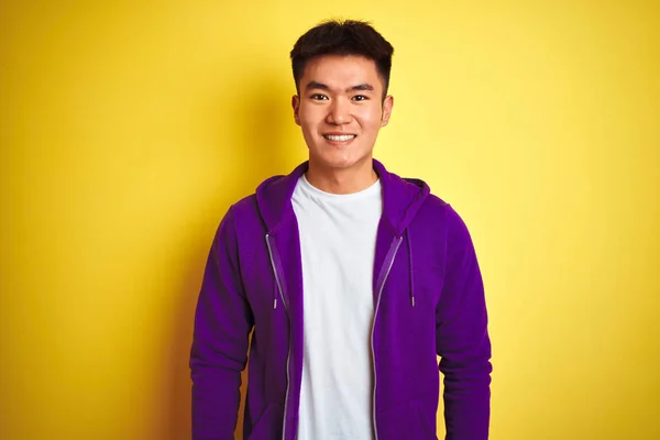 紫色のスウェットシャツを着たアジアの若い中国人男性が 孤立した黄色の背景の上に立ち 幸せでクールな笑顔を浮かべていた ラッキーな人 — ストック写真