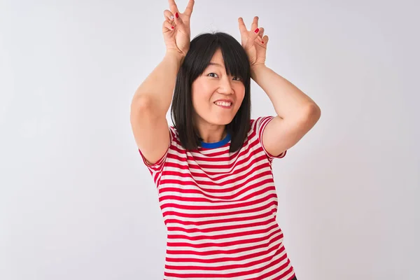 孤立した白い背景の上に赤いストライプのTシャツを着ている若い美しい中国人女性は バニー耳として頭の上に指で面白いとクレイジーポーズ 陽気な笑顔 — ストック写真
