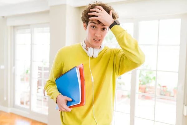 年轻的学生男子戴着耳机 拿着笔记本 手放在头上 羞愧而惊讶 愤怒和沮丧 因错误而感到恐惧和不安 — 图库照片