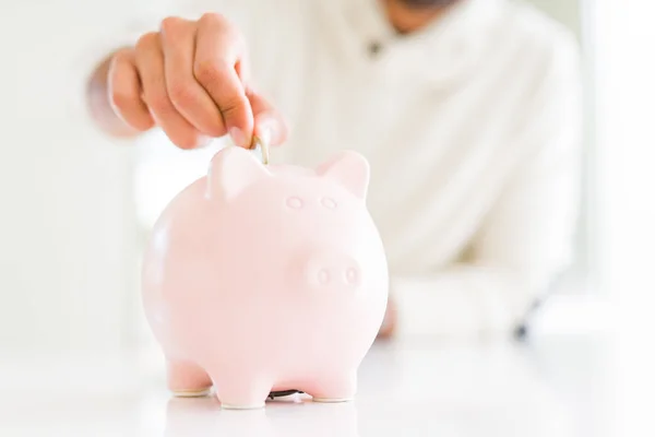 Man putting a coin inside of piggy bank saving for investment