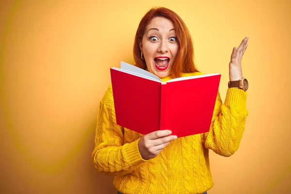 Joven Profesora Pelirroja Leyendo Libro Rojo Sobre Fondo Amarillo Aislado — Foto de Stock