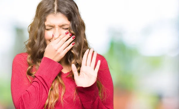 赤いセーターを着た若い美しい女性は 鼻に指で息を保持し 臭いと嫌な 耐え切れない臭いを嗅ぐ 悪臭の概念 — ストック写真