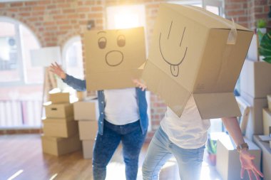 Komik emoji ile karton kutular giyen çılgın çift kafa üzerinde yüzler, yeni evde eğlenmek