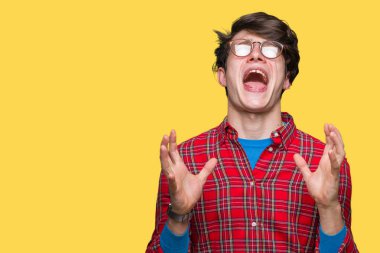 Üzerinde gözlük takan genç yakışıklı adam arka plan deli izole ve deli bağırarak ve agresif ifade ve silah kaldırdı bağırıyor. Hayal kırıklığı kavramı.