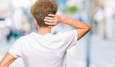 Geriye doğru elle kafasında şüphe hakkında düşünme casual beyaz t-shirt giyen afro saçlı Genç yakışıklı adam