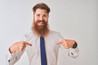 Genç kızıl saçlı İrlandalı işadamı izole beyaz arka plan üzerinde duran yüzünde gülümseme ile emin görünümlü, parmakları gururlu ve mutlu kendini işaret.