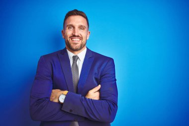 Mavi izole arka plan mutlu yüz üzerinde genç yakışıklı iş adamı kameraya bakarak çapraz kolları ile gülümseyerek. Pozitif kişi.