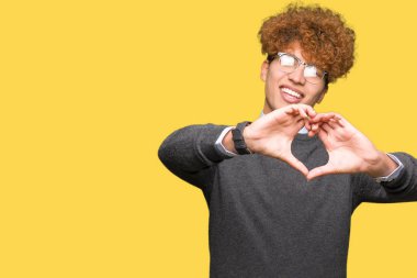 Afro saçlı gözlüklü aşık kalp simgesi ve elleriyle şekil gösteren gülümseyen genç yakışıklı iş adamı. Romantik kavramı.