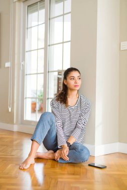 Evde katta oturan genç güzel kadın kendine güvenen gülümseme ile doğal yüz pozuyla profil rahatla tarafına, seyir.